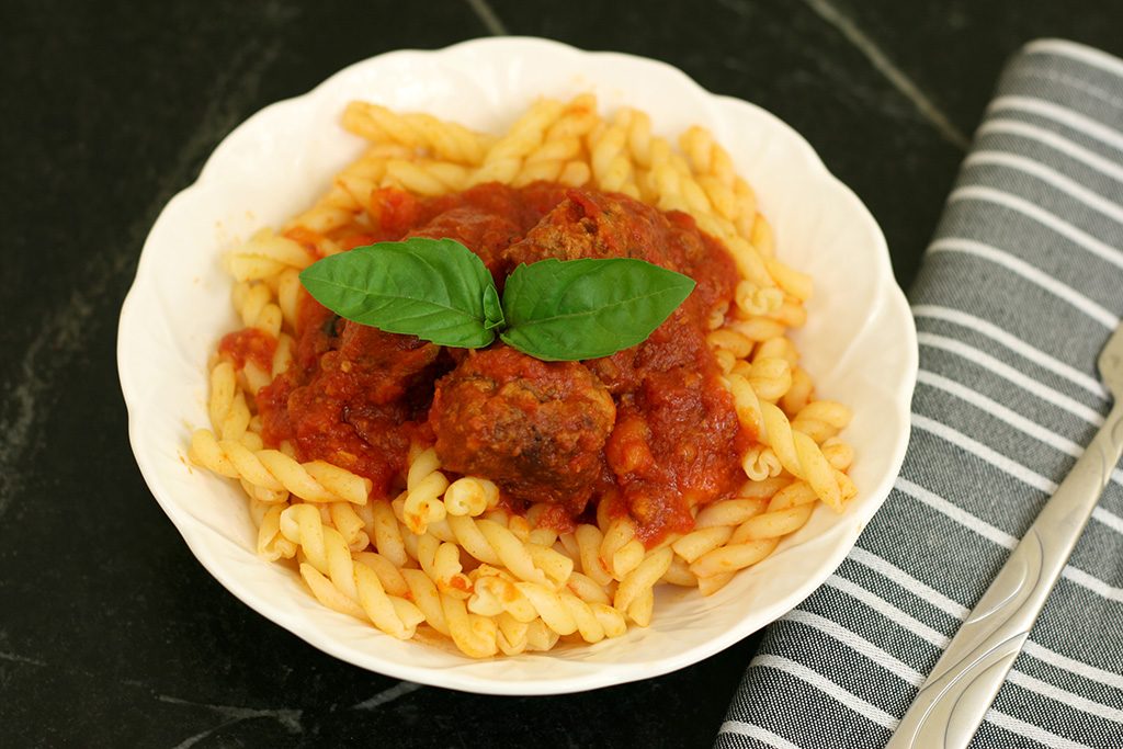 Italian meatballs with sauce over pasta in a bowl