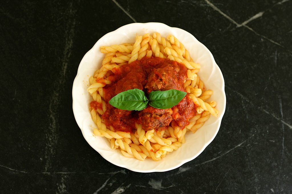 Italian Meatballs and sauce over pasta in a bowl.